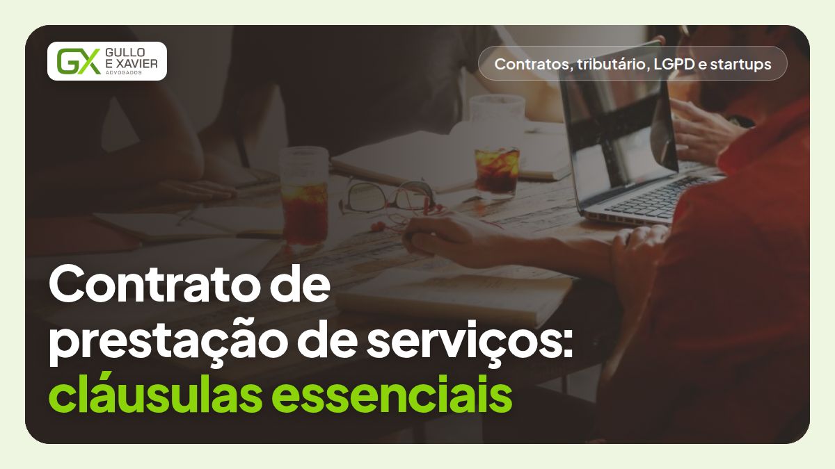 Duas pessoas em reunião de trabalho revisando um contrato sobre a mesa de um escritório, com o título do artigo sobre cláusulas essenciais.